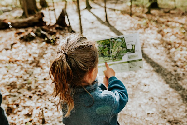Girl in a forest pointing at a map