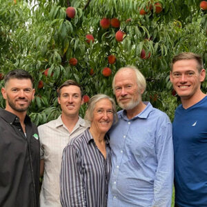 Smiling family in front of a peach tree