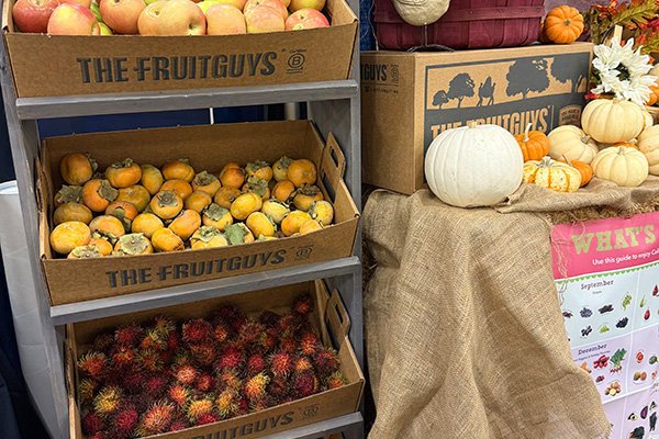 Produce on display at The FruitGuys' booth, apples, persimmons, and rambutans