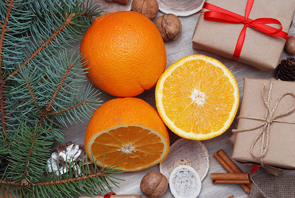 Whole and cut orange surrounded by holiday items