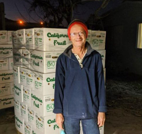 Farmer standing in front of boxes of fruit