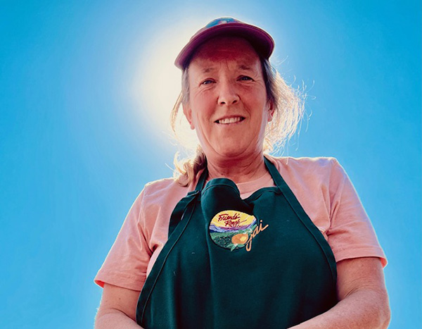 Smiling woman in a Friend's Ranches Ojai apron against blue sky